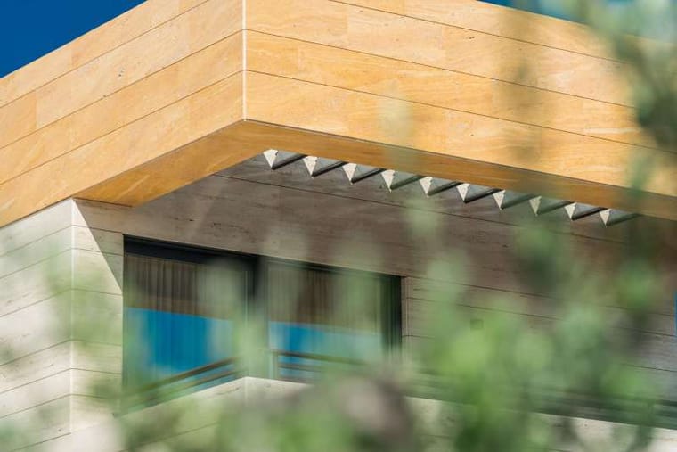 Detalj krovnog vijenca obloženog zlatnožutim travertinom iznad svijetle kamene fasade, Markvinia Biograd na Moru